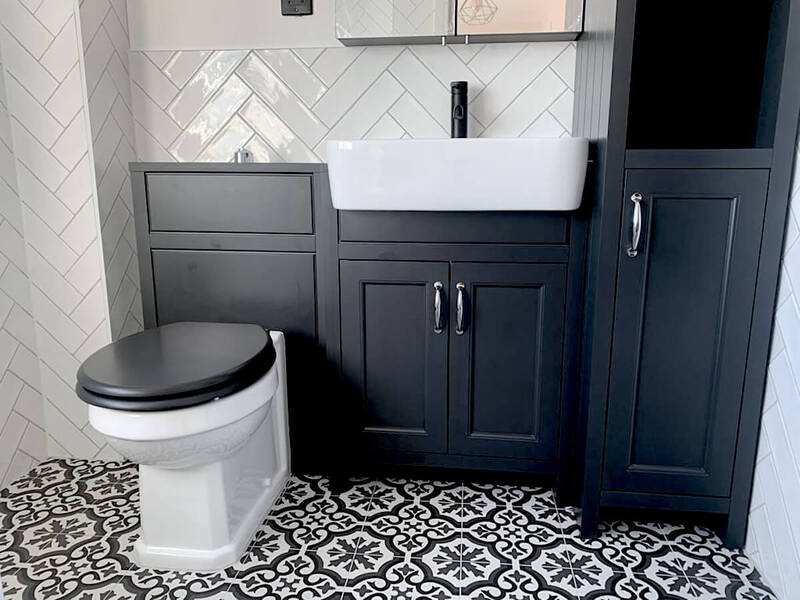Elegance meets function in this St Albans bathroom featuring a charcoal vanity unit with a contemporary basin and contrasting herringbone wall tiling, set above traditional patterned flooring
